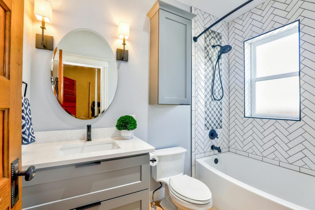 Elegant modern bathroom featuring chevron tiles, oval mirror, and sleek fixtures for a contemporary look.