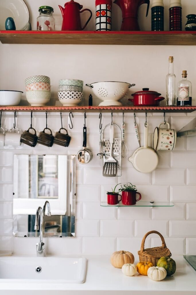 Cozy kitchen shelf with hanging utensils, colorful bowls, and rustic decor creating a warm atmosphere.